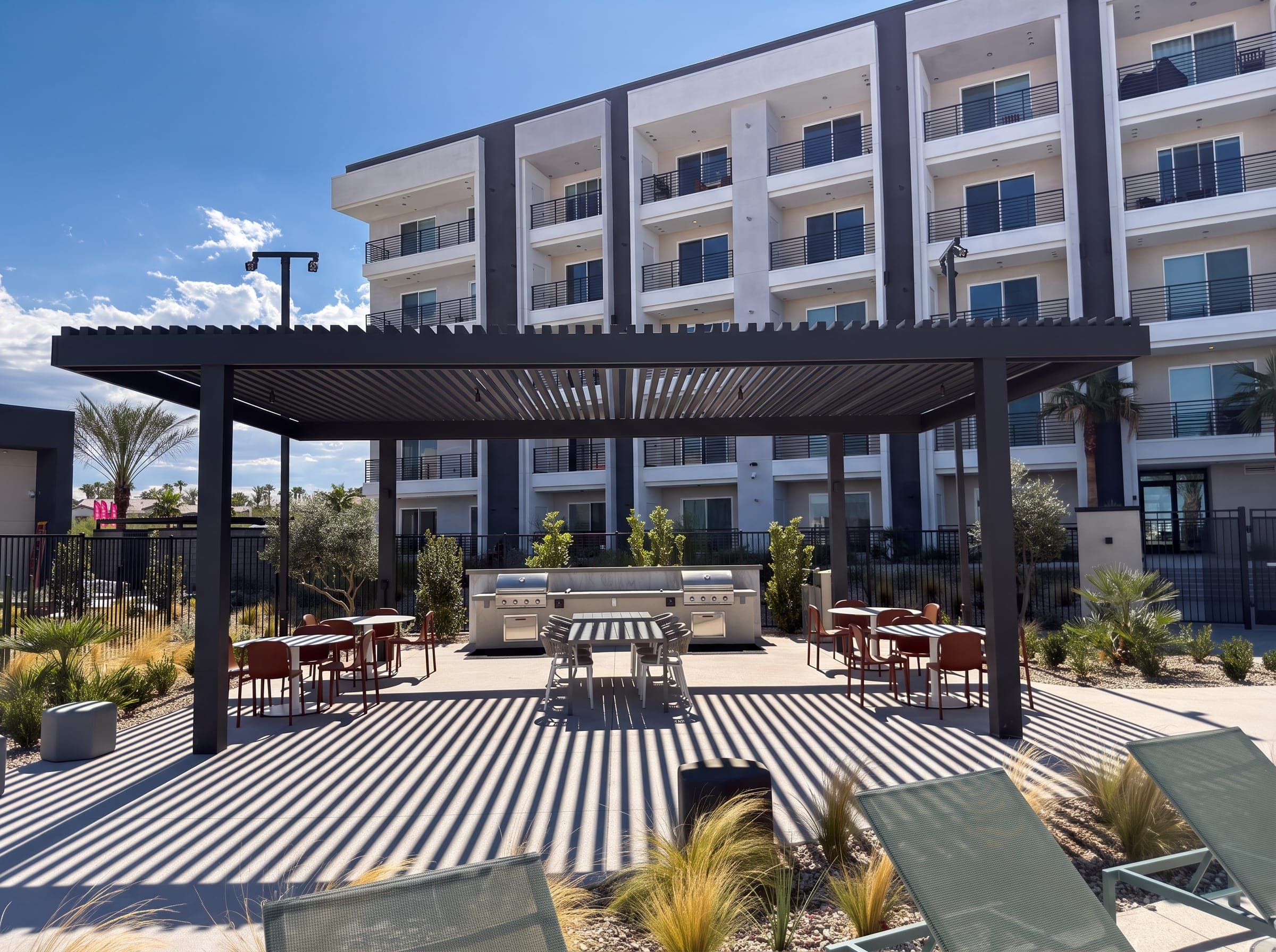 Espresso lattice-top pavilion over an outdoor kitchen and dining tables at ARCA Apartments