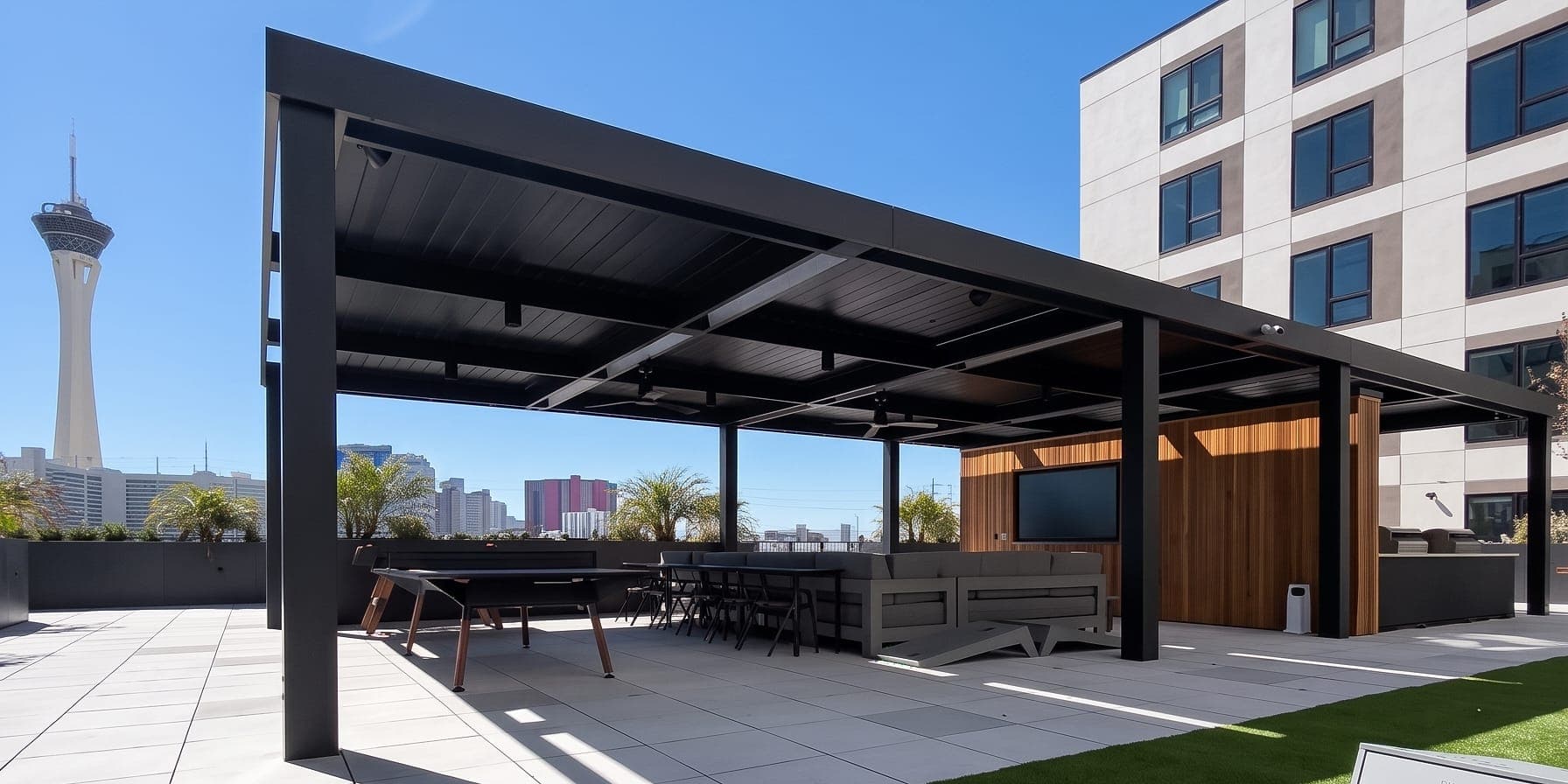 Black louvered roof structure on an apartment rooftop deck, with the Strat tower in the distance