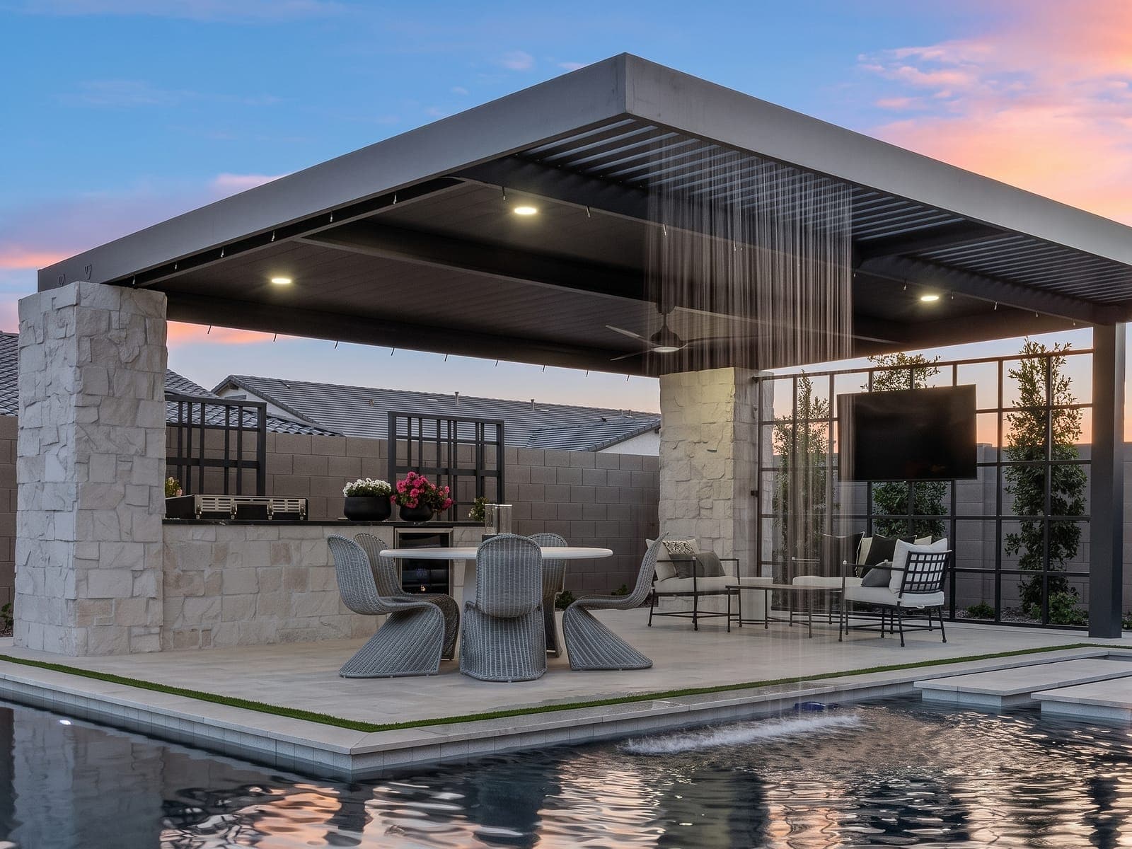 Combo lattice and VEER panel pergola with a rain curtain beside a pool at dusk